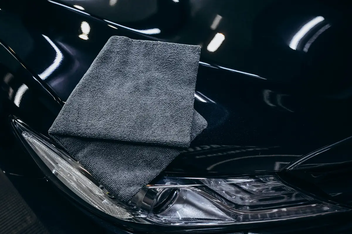 A gray microfiber cloth on a glossy black car hood.