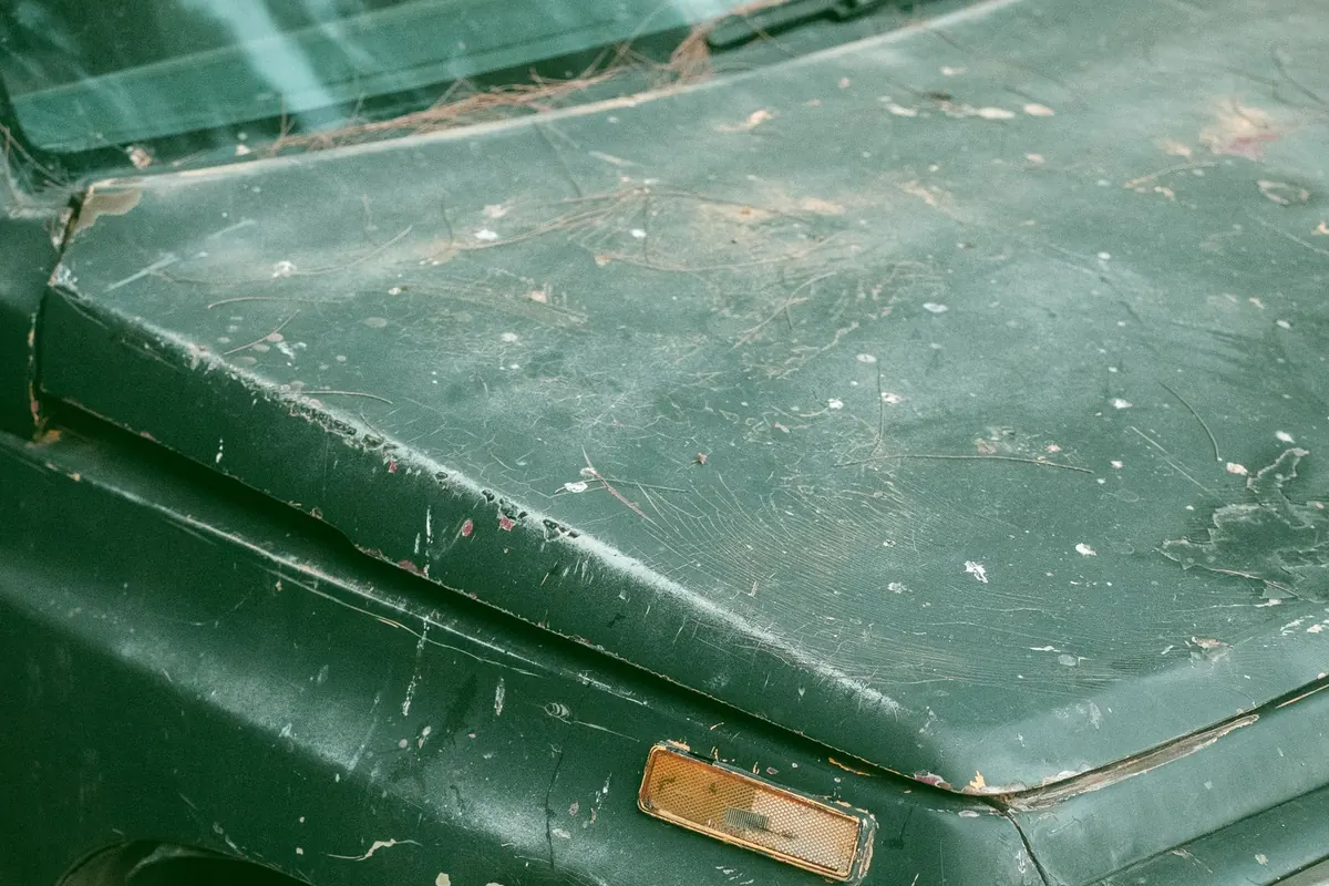 Close-up of worn, scratched car paint in daylight.