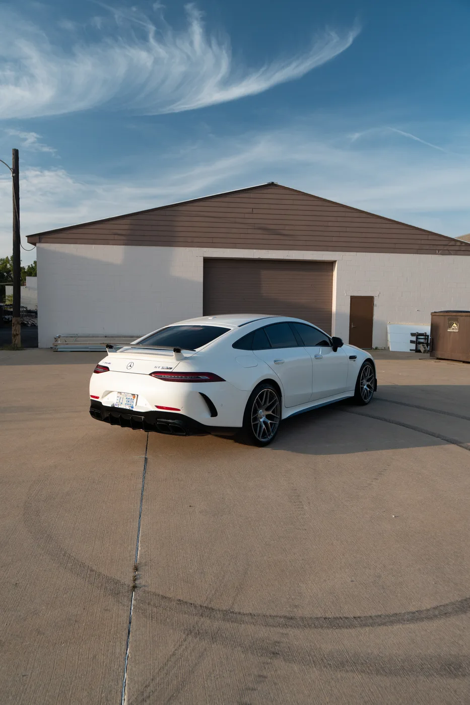 A white Mercedes-AMG GT four-door coupe under a blue sky